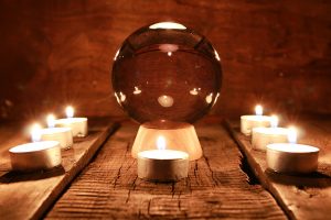 Bola de cristal para predecir el destino y la acción sobrenatural en la mesa de la vieja caoba con velas y tarjetas